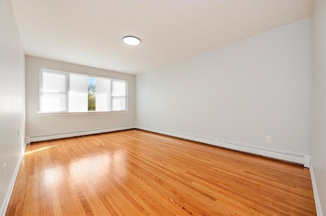 unfurnished room featuring light hardwood / wood-style floors and a baseboard heating unit