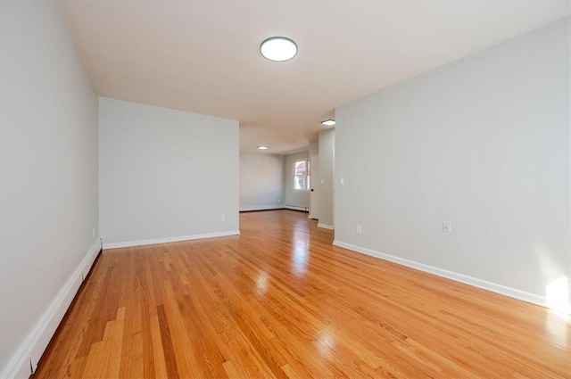 empty room featuring a baseboard radiator and light wood-type flooring