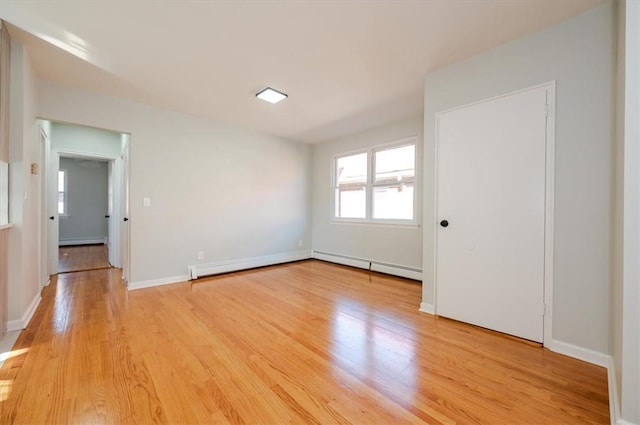 spare room with a baseboard heating unit and light hardwood / wood-style flooring