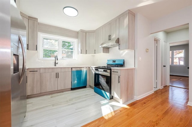 kitchen with sink, light wood-type flooring, light brown cabinets, and appliances with stainless steel finishes