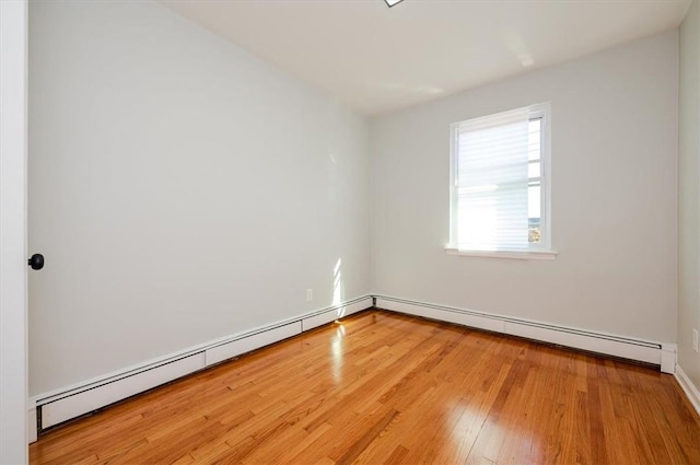 unfurnished room with hardwood / wood-style floors and a baseboard radiator