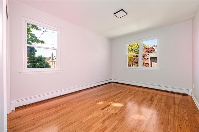 unfurnished room featuring light wood-type flooring and a baseboard heating unit