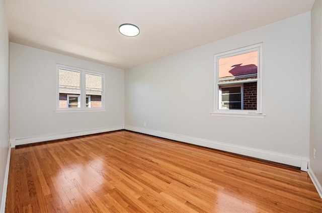 empty room featuring a baseboard heating unit and light hardwood / wood-style flooring