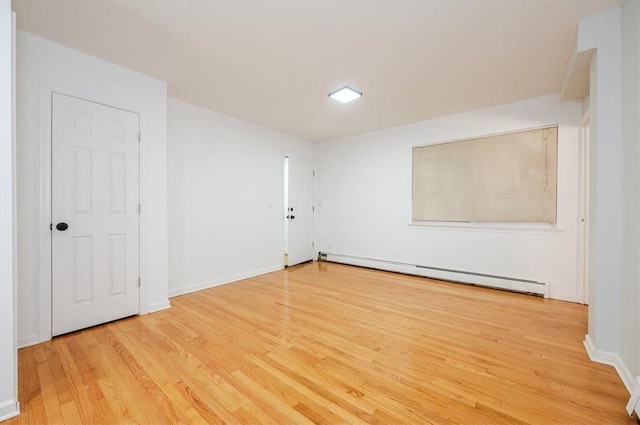 unfurnished room featuring baseboard heating and light wood-type flooring