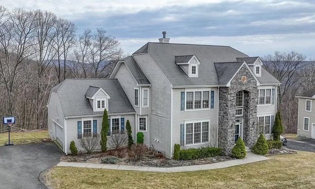 cape cod home featuring a garage and a front lawn