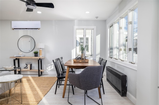 dining area with ceiling fan, a wall unit AC, light wood-type flooring, and radiator