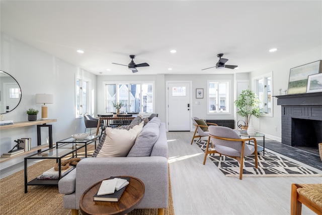 living room featuring ceiling fan, a fireplace, and light hardwood / wood-style flooring