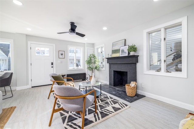 living room featuring ceiling fan, radiator heating unit, wood-type flooring, and a fireplace