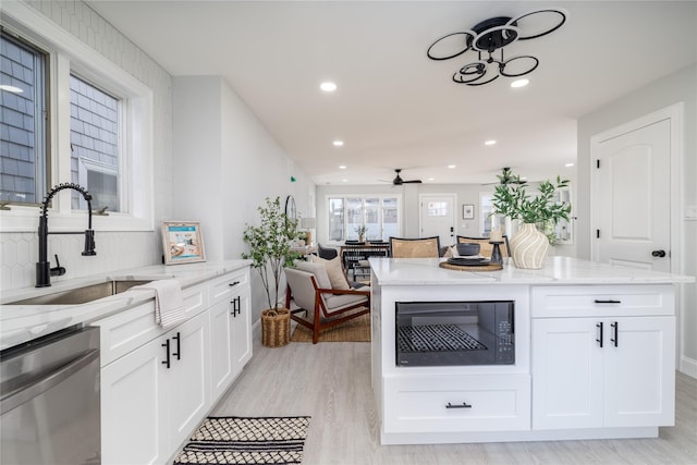 kitchen featuring built in microwave, sink, light hardwood / wood-style flooring, stainless steel dishwasher, and white cabinets