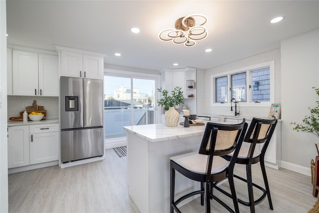 kitchen featuring stainless steel fridge with ice dispenser, white cabinets, and light wood-type flooring