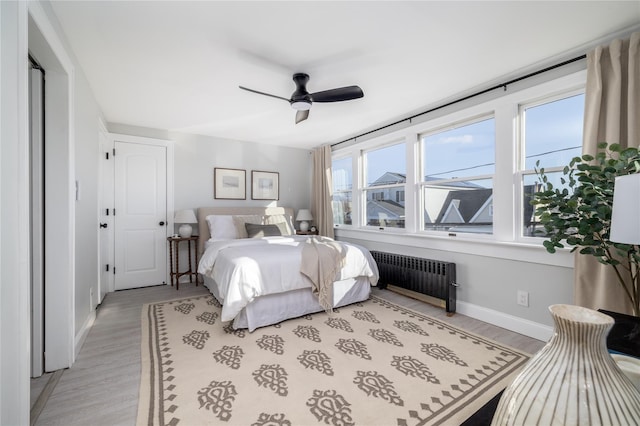 bedroom featuring ceiling fan, light wood-type flooring, and radiator