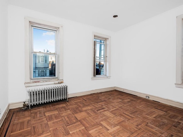 unfurnished room featuring radiator heating unit and dark parquet floors