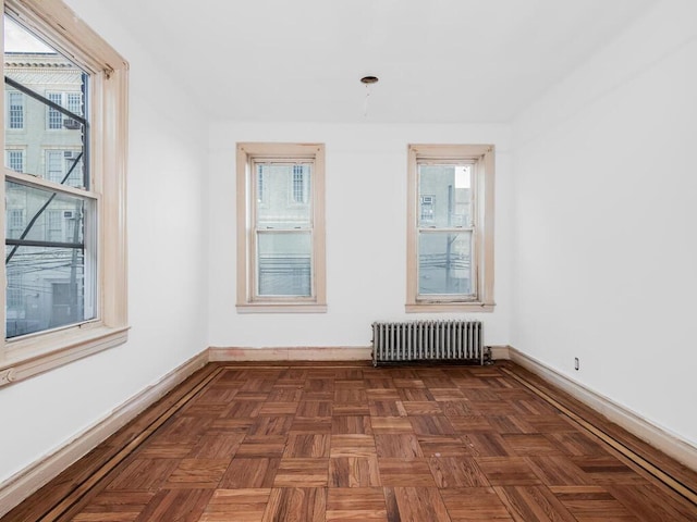 empty room with radiator heating unit and dark parquet floors