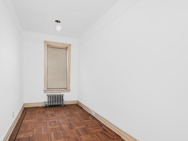 spare room with dark parquet flooring and radiator heating unit