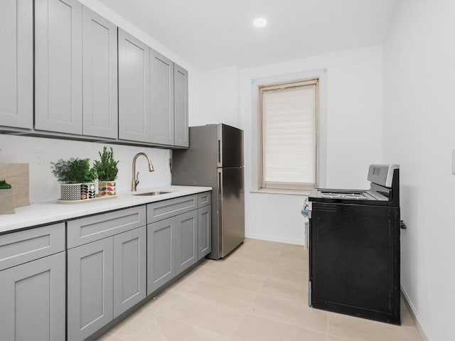 kitchen featuring gray cabinetry, sink, stainless steel fridge, electric stove, and light tile patterned flooring