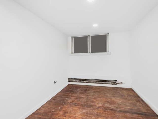 empty room featuring dark hardwood / wood-style floors and a baseboard radiator