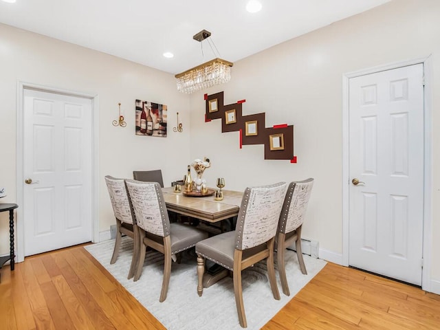 dining space with light wood-type flooring and an inviting chandelier