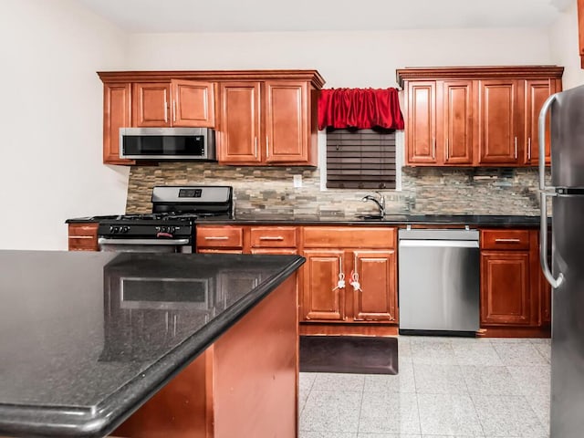 kitchen featuring decorative backsplash, sink, stainless steel appliances, and dark stone counters