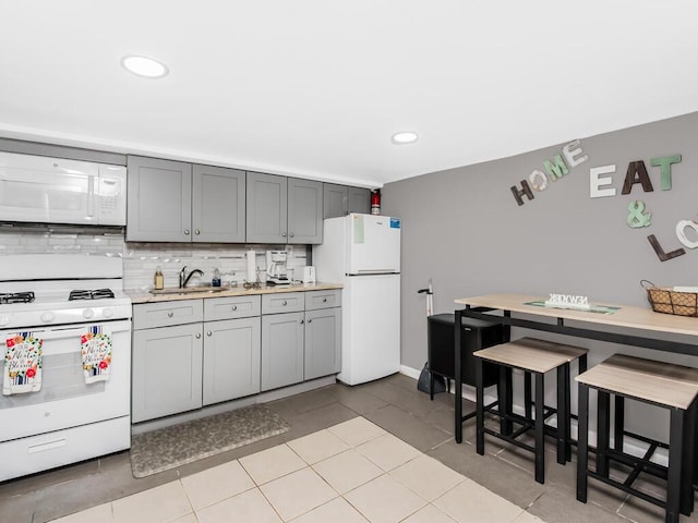 kitchen with white appliances, sink, gray cabinets, light tile patterned floors, and tasteful backsplash