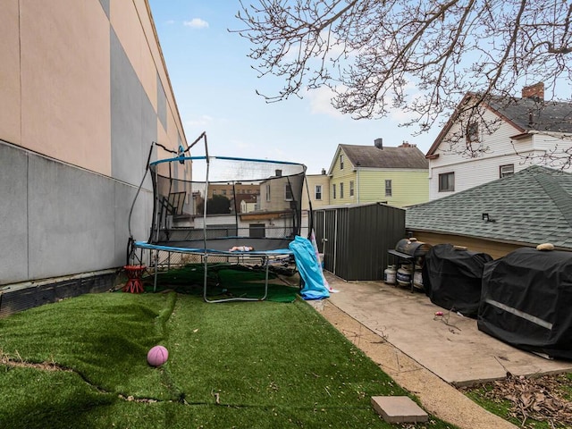 view of yard with a trampoline and a patio