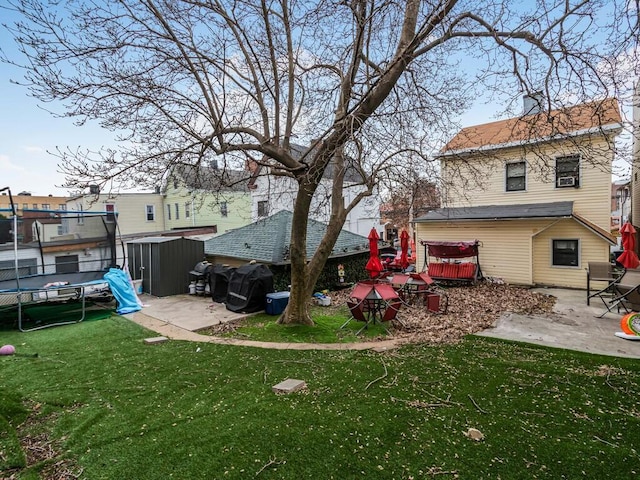 view of yard with a trampoline and a patio