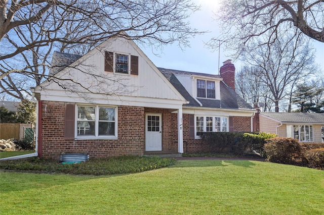 view of front of house with brick siding, a front lawn, and a chimney