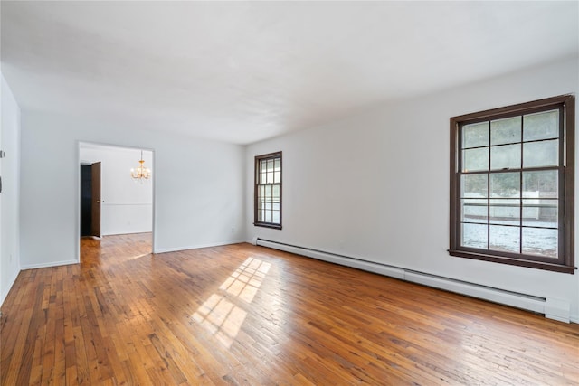 unfurnished room with hardwood / wood-style flooring, a baseboard radiator, and a notable chandelier