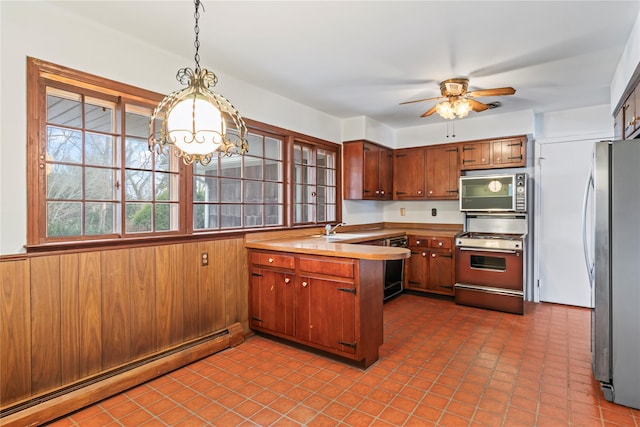 kitchen with wood walls, stainless steel fridge, hanging light fixtures, stove, and a baseboard heating unit