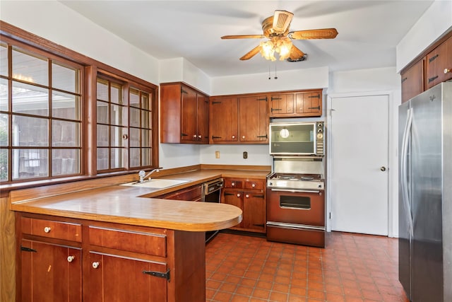 kitchen featuring sink, stainless steel refrigerator, kitchen peninsula, ceiling fan, and stove