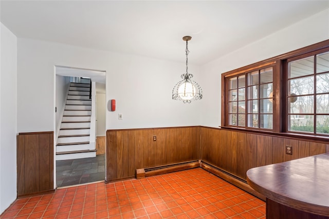 unfurnished dining area featuring a baseboard radiator and wood walls