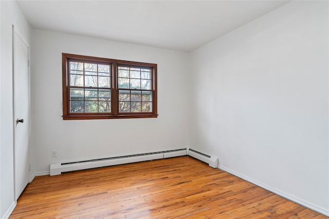 unfurnished room featuring baseboard heating and light hardwood / wood-style floors