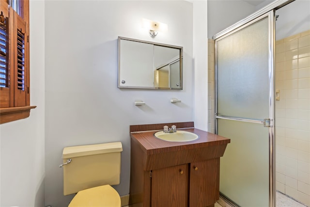 bathroom featuring vanity, toilet, and a shower with shower door