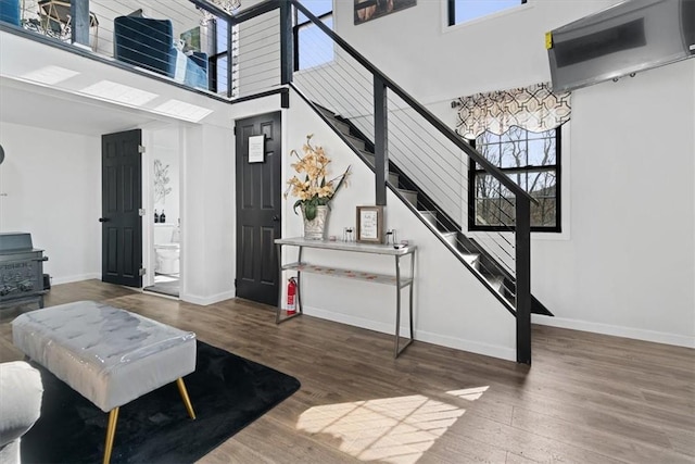 interior space with dark hardwood / wood-style flooring, a high ceiling, and a wall mounted AC