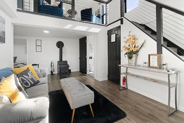 living room featuring dark hardwood / wood-style flooring, a towering ceiling, and a wood stove