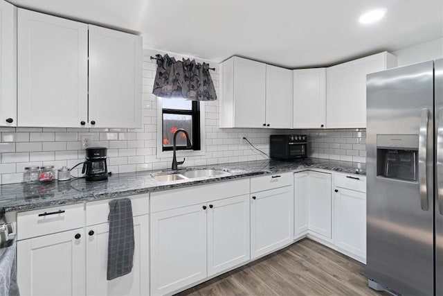 kitchen featuring stainless steel fridge, white cabinetry, and sink