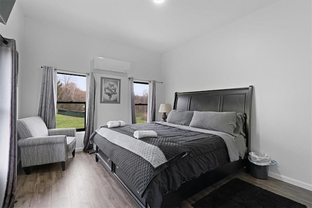 bedroom featuring hardwood / wood-style floors, multiple windows, and a wall mounted AC