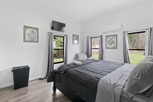 bedroom with light wood-type flooring and an AC wall unit