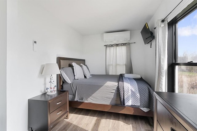 bedroom with light hardwood / wood-style floors and a wall unit AC