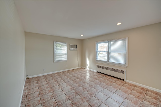 empty room featuring radiator heating unit, a wall mounted AC, and light tile patterned floors