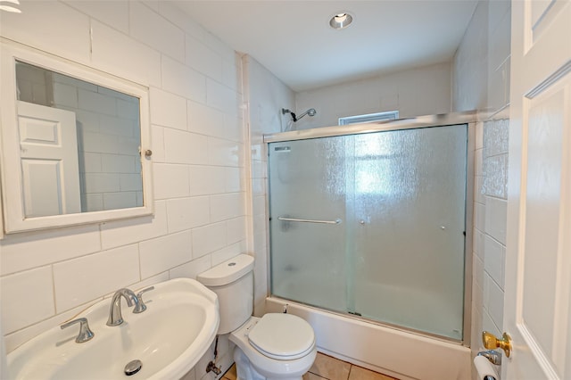 full bathroom featuring enclosed tub / shower combo, sink, backsplash, tile walls, and toilet