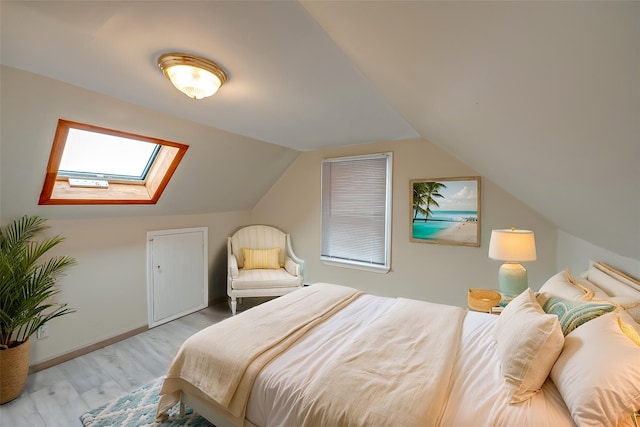 bedroom with vaulted ceiling with skylight and light wood-type flooring