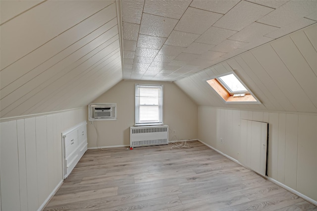 bonus room with light wood-type flooring, radiator, lofted ceiling, and a wall unit AC