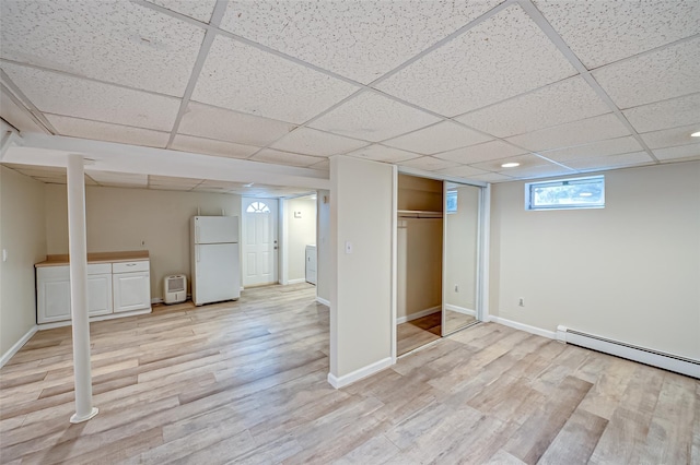 basement featuring a drop ceiling, light hardwood / wood-style flooring, a baseboard radiator, and white fridge