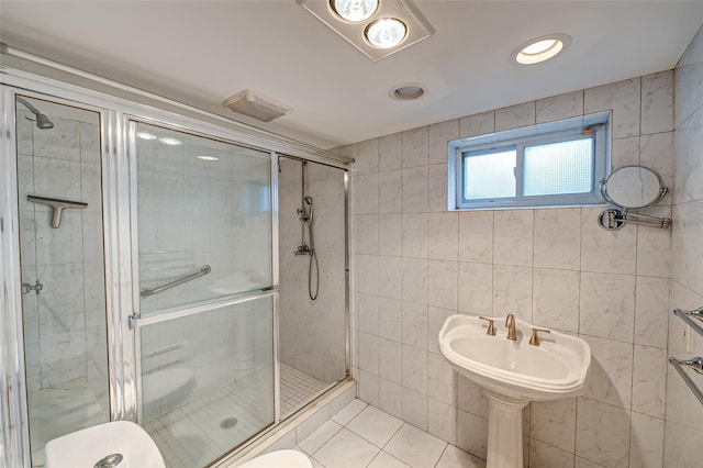 bathroom with tile patterned floors, toilet, tile walls, and an enclosed shower