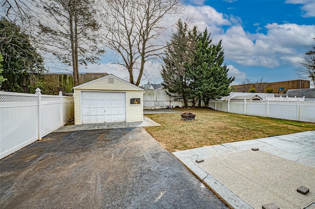 view of yard featuring a fire pit, a garage, and an outdoor structure