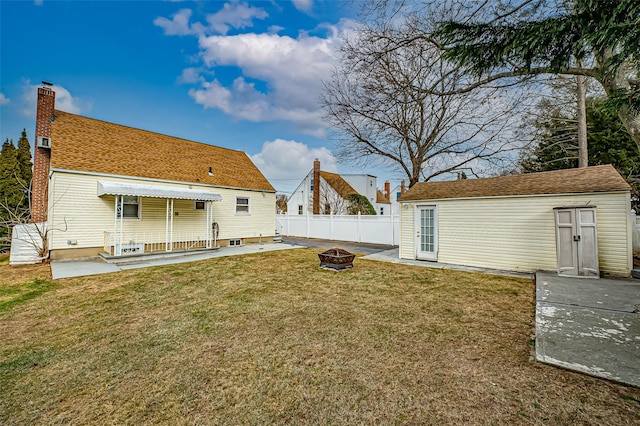 back of house with a fire pit, an outbuilding, a patio, and a yard