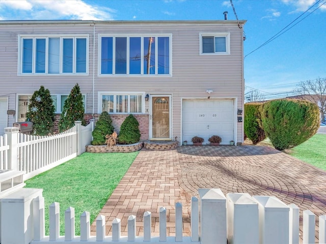 view of property featuring a garage and a front lawn