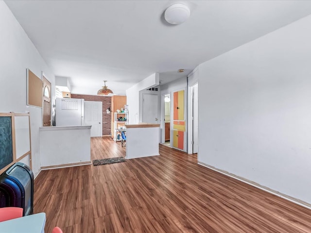 unfurnished living room with wood-type flooring and brick wall