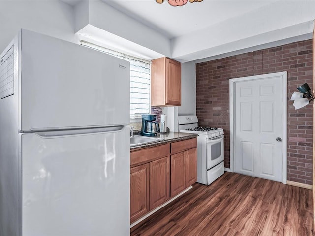 kitchen featuring brick wall, dark wood-type flooring, white appliances, and sink