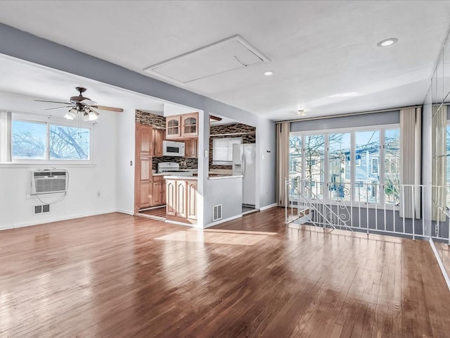 unfurnished living room featuring light hardwood / wood-style floors, an AC wall unit, and ceiling fan